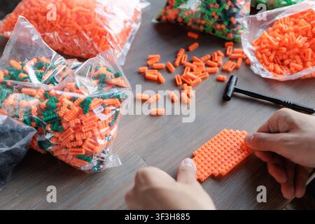 Hands assembling vibrant plastic construction blocks, ideal for enhancing fine motor skills and logical thinking in children through creative play and Stock Photo