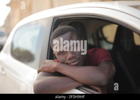 Young man smiles while leaning out his car window Stock Photo