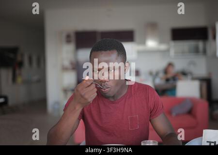 Young Black man eating a meal at home Stock Photo