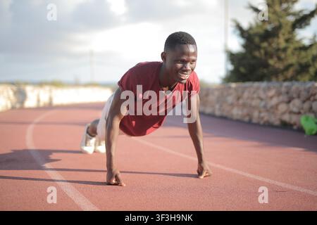 Young Black man smiling while doing pushups outdoors Stock Photo