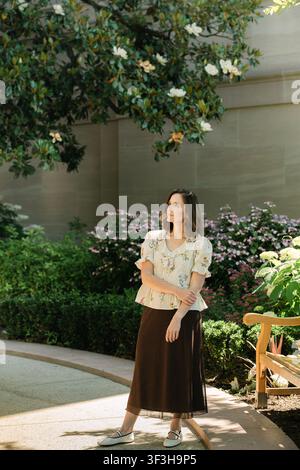 Thoughtful woman standing under a magnolia tree Stock Photo