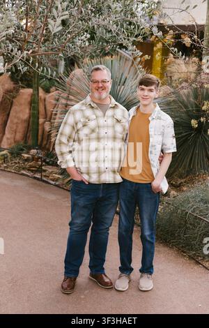 Smiling father and teen son stand together outdoors Stock Photo