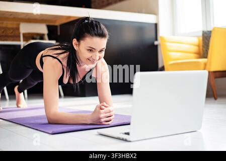 Smiling woman using laptop for training at home Stock Photo