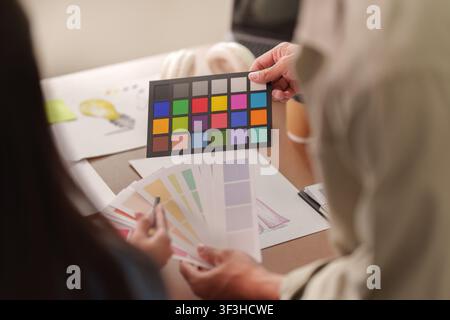 Creative designers choosing color swatches and calibration card in studio Stock Photo