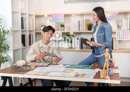 Asian fashion designers collaborating on color palette in creative studio Stock Photo