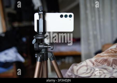 A white smartphone mounted on a mobile tripod with soft blur background Stock Photo