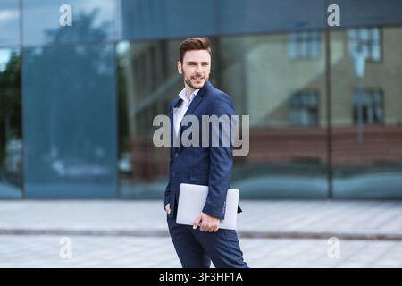 Attractive businessman holding tablet computer on city street Stock Photo