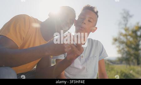 Father and son smile and laugh while playing together in nature during golden hour. Stock Photo