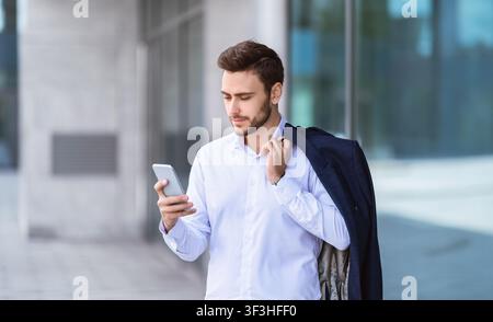 Serious business executive checking his mail on cellphone near office center at city Stock Photo