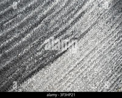 This closeup image features a textured surface covered in intricate ice crystals, highlighted by natural light and shadow patterns Stock Photo