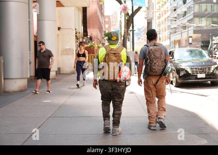 Toronto, Canada - June 23, 2026: Construction workers walking on busy downtown sidewalk Stock Photo