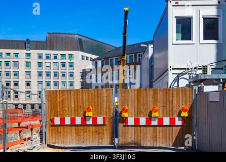Construction site entrance with closed wooden barrier gate warning lights and modular container offices in city Stock Photo