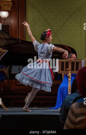 Vienna, Austria - June 9, 2023: Young female ballet dancer performing on stage in Vienna concert hall, wearing blue polka dot dress with flowers in ha Stock Photo