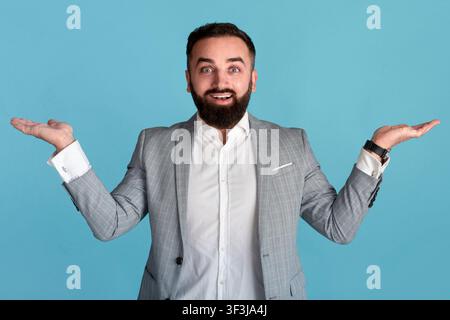 Joyful businessman presenting or comparing products, making scales gesture with hands over blue background, copy space Stock Photo