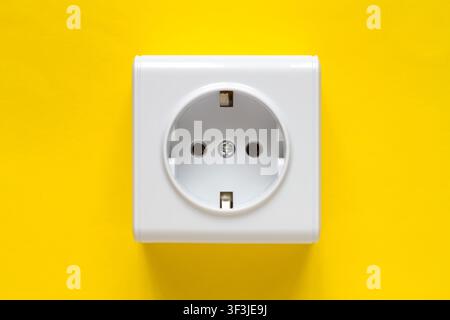 White electrical outlet on a yellow background. A close-up of a new electrical outlet. Stock Photo
