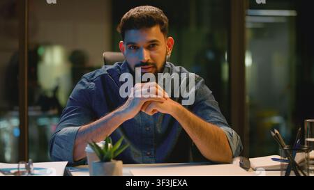Web camera view Indian business man smiling talking looking at camera video call at night dark evening office Arabian businessman Hindu male guy Stock Photo