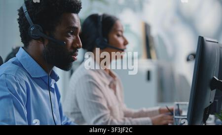 Two busy concentrated multiethnic business colleagues working in call center communicating with clients online consultation in agency. Team diversity Stock Photo
