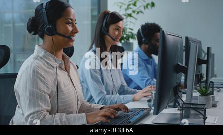 Three multiethnic business workers team talking working in callcenter helping clients distant. African American businesswoman smile talk work with Stock Photo