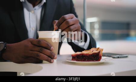 Unknown African American business man stirring mixing sugar with wooden stick preparing drink coffee herbal tea remedy in cafe male unrecognizable Stock Photo