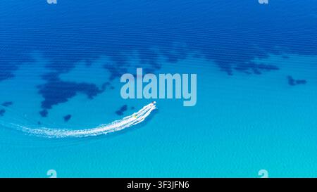 Possidi beach, Greece 11 July 2026. A white speedboat makes a sharp turn creating white foam trails on the clear turquoise sea near Possidi beach in G Stock Photo