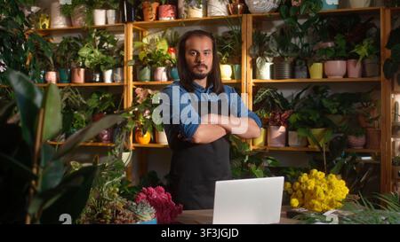 Portrait of confident professional caucasian male worker at florist shop looking at camera posing with crossed arms. Beautiful young adult man florist Stock Photo