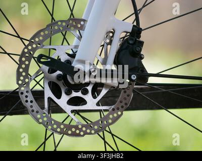 Close-up of bicycle disc brake rotor and caliper on front wheel, hydraulic braking system detail. Stock Photo