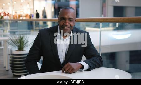 African American mature business man in cafe at table optimistic smiling looking at camera at cafeteria 50s businessman male visitor client positive Stock Photo