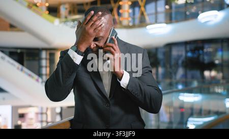 African American middle-aged business man answer call upset frustrated talking mobile phone hearing bad news sad mature businessman male executive Stock Photo