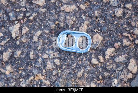 Aluminum beverage can pull tab (pop tab) on the pavement. Even though it is the most beautiful environment in the world with the biggest tropical fore Stock Photo