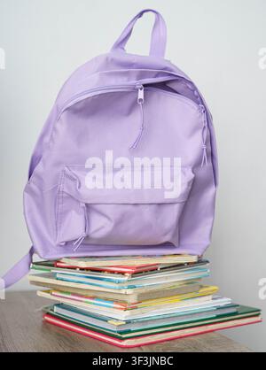 Purple school backpack placed on a desk with notebooks and colorful markers, ready for a new school day. Stock Photo