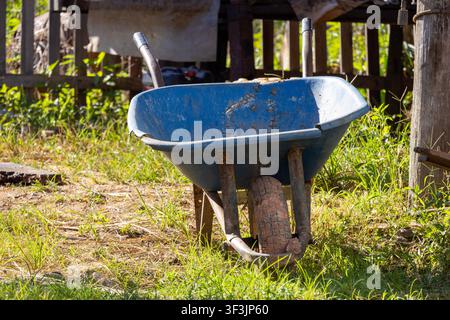 Old green plastic bucket on recently mown lawn close to a wooden fence; it's been fixed a couple of times, and it has resisted the passing of time. Stock Photo