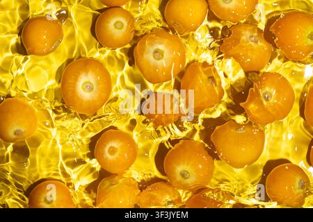 Fresh physalis berries in water splash for refreshing food concept. Stock Photo