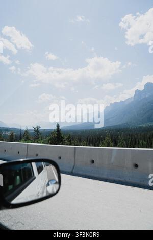 View of the Rocky Mountains and pine forest seen from a car window along a highway in Canmore, Alberta, Canada. Stock Photo