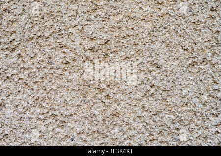 Rough exposed aggregate concrete wall texture with granular surface. Stock Photo