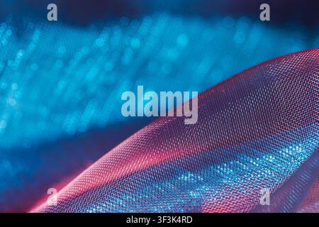 Close-up of translucent net fabric with vibrant blue and red tones, soft focus, and bokeh Stock Photo