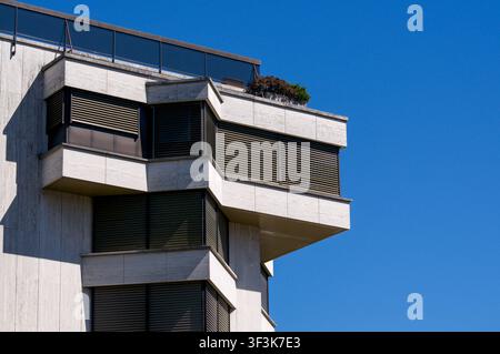 Low angle architectural detail of a modern residential building facade in Cassarate, Lugano. Close up view of stone balconies and window blinds Stock Photo