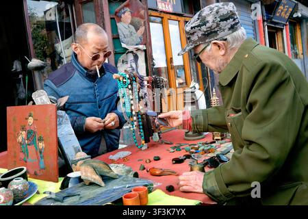 Chinese man with round sunglasses and cigarette, second hand stall, Ancient City of Pingyao, Shanxi Province, China, Asia Stock Photo