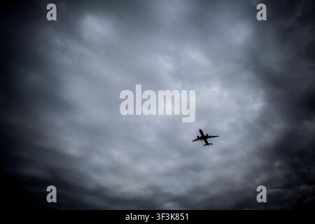 Passenger Airplane Flying Through Dark Stormy Sky and Heavy Clouds Stock Photo