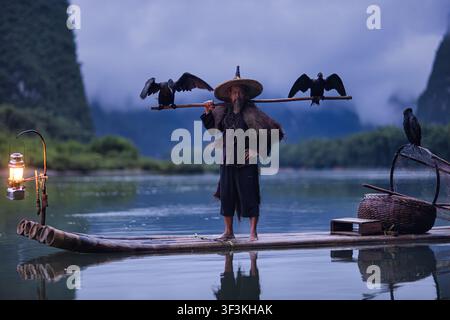Guilin, Guangxi, China - 18 June 2026: View of a traditional cormorant fisherman on a bamboo raft with cormorants on the Li River near Xingpingzhen, w Stock Photo