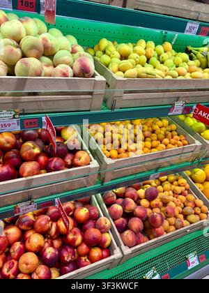 23.07.2026 Ukraine, Kharkov Shelves with fresh peaches, nectarines, and apricots in wooden crates at market Stock Photo
