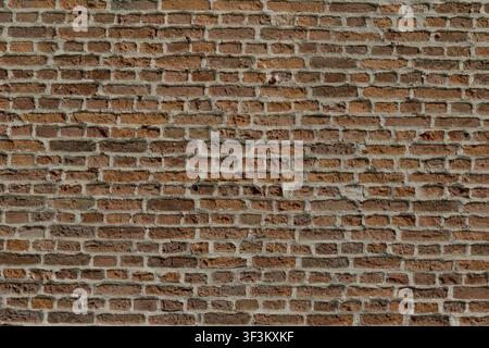 An exterior wall section of an old brick church, displaying varying shades of weathered red brick and sturdy mortar lines. Stock Photo