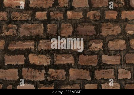 A texture view of an old red brick wall with thick, dark mortar lines between the bricks. Stock Photo