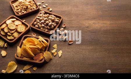 Rusks, chips, nuts and pistachios. Snacks in plates on table background Stock Photo