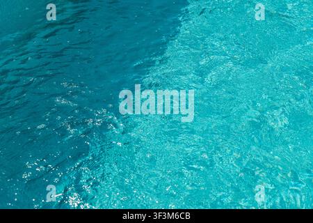 Close-up view of clear blue water in a swimming pool, showing subtle ripples and shimmering light patterns Stock Photo