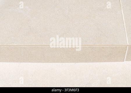 A detailed, abstract perspective of two levels of beige textured tiles, showcasing their surface and the fine lines between them Stock Photo