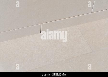 A detailed perspective of light beige stone tiles with a subtle granular texture, showcasing their precise arrangement and clean grout lines Stock Photo