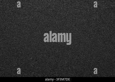 Texture of black synthetic sponge foam rubber sheet close up background. Stock Photo
