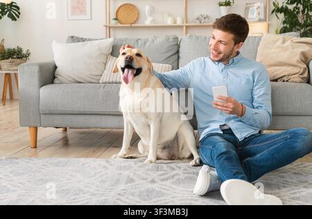 Portrait of young man with dog using cell phone Stock Photo