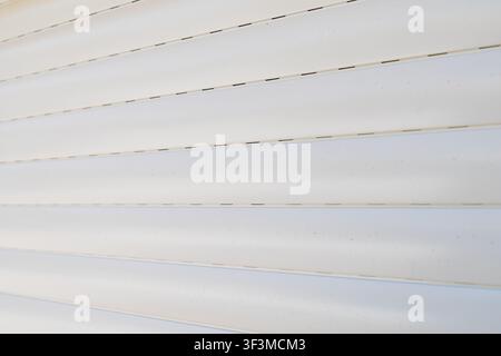 A detailed abstract background showcasing the clean lines and subtle texture of white horizontal window blinds, creating a sense of order and simplici Stock Photo