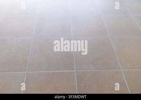 A seamless perspective view of large, square beige floor tiles with fine white grout lines, suggesting a modern and clean interior space Stock Photo